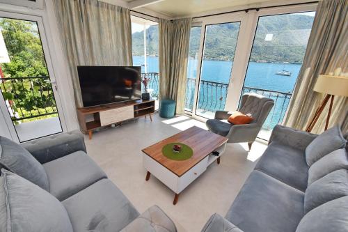 a living room with a couch and a tv and a table at Apartments Krivokapic in Perast
