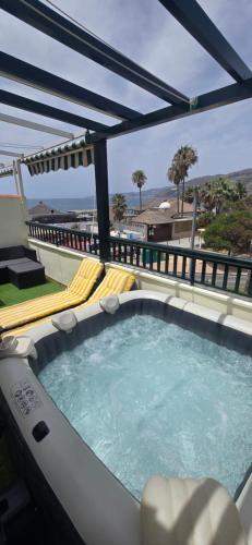 a hot tub on a patio with chairs and an umbrella at Terraza al mar in Salobreña