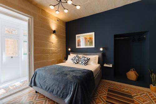 a bedroom with blue walls and a bed with pillows at Ta' Dolor - Kalkara Heritage Maisonette in Kalkara