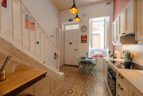 a kitchen with a staircase and a table in it at Ta' Dolor - Kalkara Heritage Maisonette in Kalkara