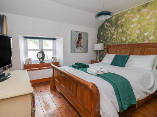 a bedroom with a wooden bed with a green accent wall at Tenandeleven Cottage in Denbigh