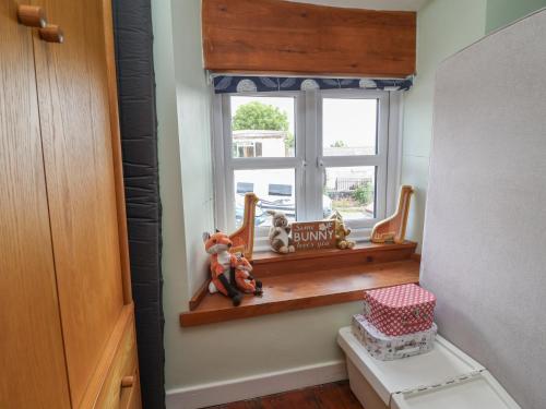 a bathroom with a window with toys on a shelf at Tenandeleven Cottage in Denbigh