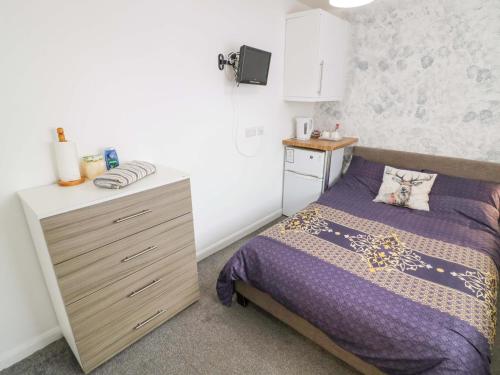 a small bedroom with a bed and a dresser at Lodge Park in Corby