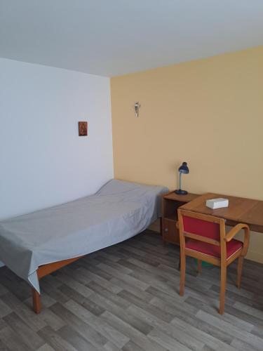 a bedroom with a bed and a desk and a chair at Hôtellerie Abbaye Port du Salut in Entrammes