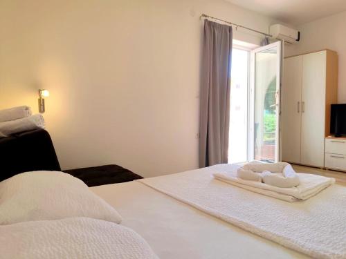 a white bedroom with a bed with towels on it at Apartments Pine in Primošten