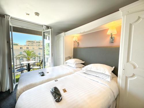 two beds in a hotel room with a balcony at Hôtel de Provence in Cannes
