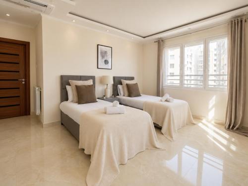 two beds in a room with white walls and windows at Appartement Spacieux à Constantine in El Khroub