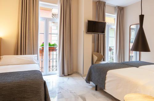 a hotel room with two beds and a window at Porcel Navas in Granada