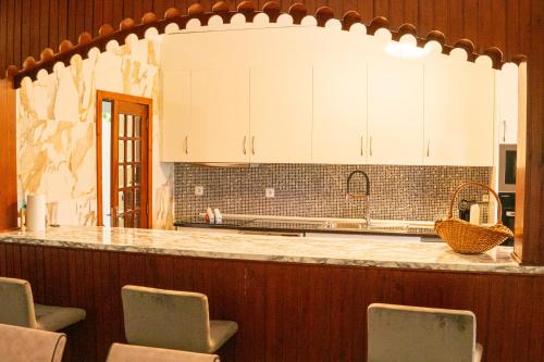 a kitchen with white cabinets and a counter with chairs at Abadia House - Geres in Geres