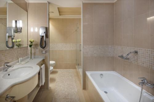 a bathroom with a tub and a sink and a toilet at UNA Hotels Expo Fiera Milano in Pero