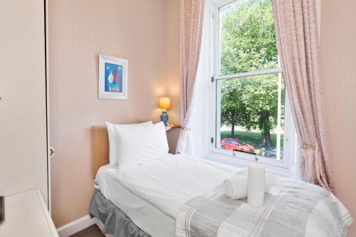 a bedroom with a white bed and a window at GuestReady - Links View in Edinburgh