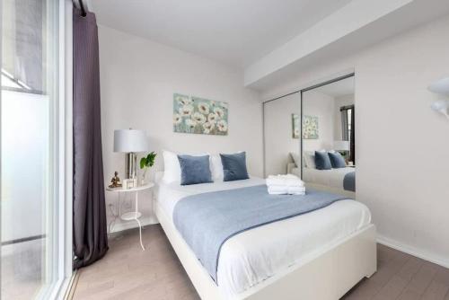 a white bedroom with a large bed and a mirror at 1 BR plus Ent District,MTCC,Jays in Toronto