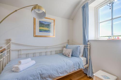 a bedroom with a bed with blue sheets and a window at Hafod in Tenby