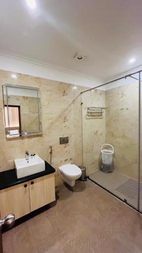 a bathroom with a sink and a toilet and a shower at Four Leaf Hotel Arjuna Manor, Varanasi in Varanasi