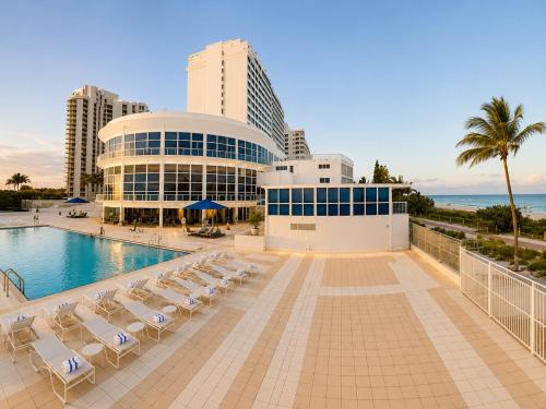 a resort with a pool and chairs and a building at SeaStays Apartments in Miami Beach