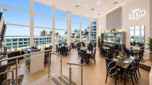 a dining room with tables and chairs and large windows at SeaStays Apartments in Miami Beach