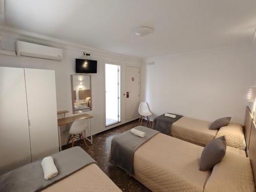 a room with three beds and a desk with a computer at AYAMONTE ROOMS 43 in Ayamonte