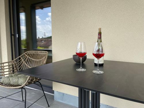 two glasses of wine and a bottle on a table at Apartment Rotmilan in Vogtsburg