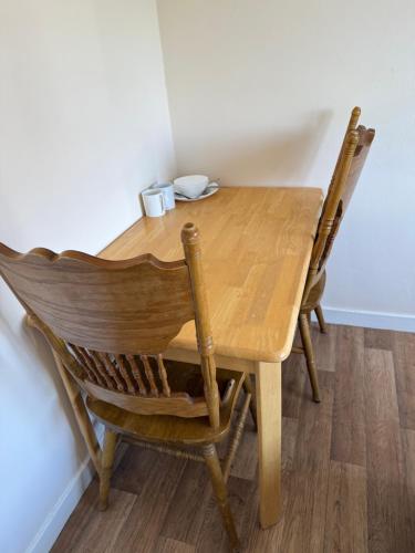 a wooden dining room table with two chairs at Kirkar Flat in Penton Mewsey