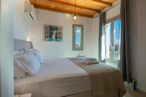 a white bedroom with a bed and a window at Amara Serifos in Serifos Chora