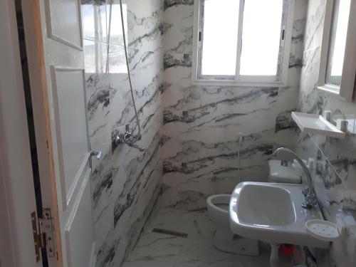 a bathroom with marble walls and a sink and a toilet at Belle vue in Aïn Draham