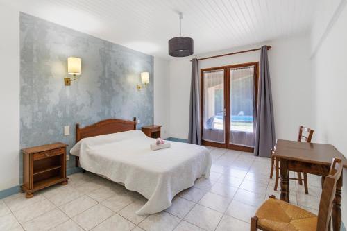 a bedroom with a bed and a table and a window at Ferme Auberge Du Roc in Saint-Pompont