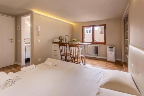 a bedroom with a large white bed and a kitchen at Central Gucciardini house in Florence