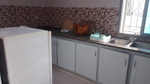 a kitchen with white cabinets and a sink and a window at appart CRISTIANA 3 Midoun in Midoun