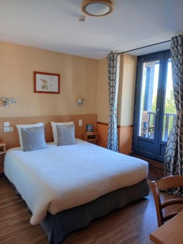 a bedroom with a large bed and a large window at Hotel Restaurant La Clairiere in Chambon-sur-Dolore