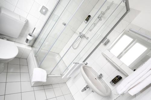 ein weißes Badezimmer mit Dusche und Waschbecken in der Unterkunft Stadthotel Jülich in Jülich