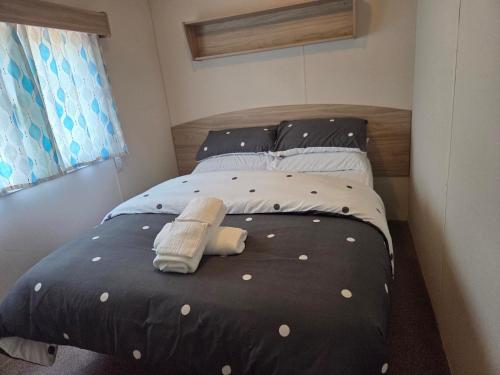 a bed with a black comforter with polka dots at Awesome Static Caravan Holiday Home in Great Billing