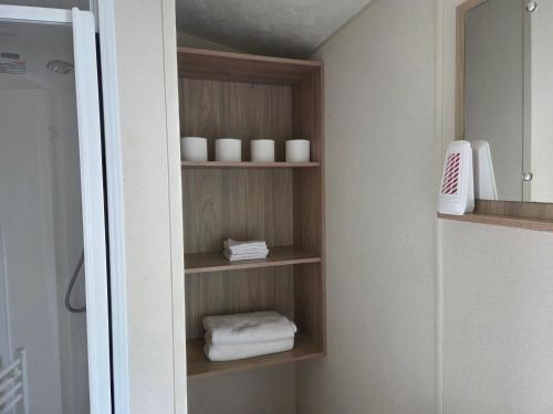 a bathroom closet with wooden shelves and white towels at Awesome Static Caravan Holiday Home in Great Billing