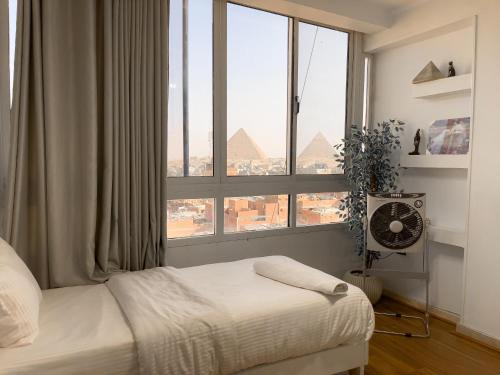 a bedroom with a bed and a large window at Luxurious GEM and PYRAMIDS view in Cairo