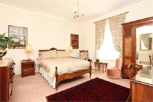 a bedroom with a bed and a table and window at Badger Towers in Cheltenham