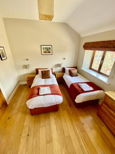 two beds in a large room with wooden floors at Decoy Country Cottages in Navan
