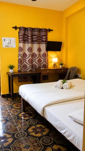 a hotel room with two beds and a desk at Samhen guest house in Majorda