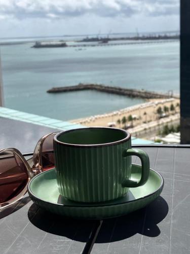 a green coffee cup sitting on a plate next to glasses at Brasil Tropical Luxury Ocean View in Fortaleza