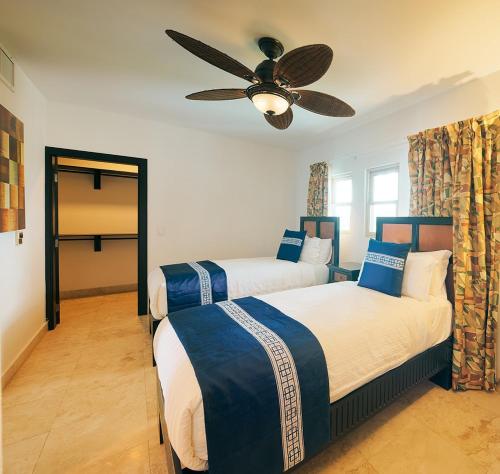two beds in a room with a ceiling fan at Las Terrazas Resort in San Pedro