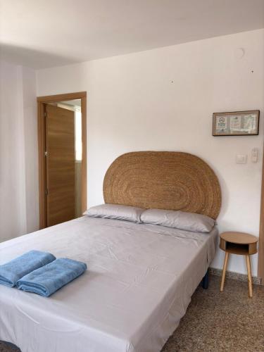 a bedroom with a white bed with a wooden headboard at Cala Queralt Rooms in Sagunto