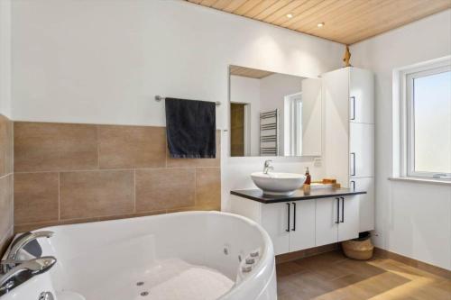 a bathroom with a tub and a sink and a mirror at 8571-Grenaa-Kaprifolievej-20 in Grenå Strand