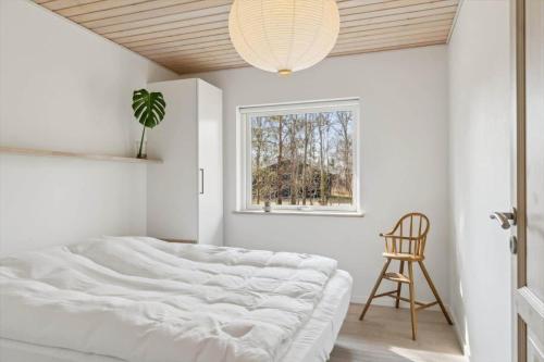 a white bedroom with a bed and a window at 8571-Grenaa-Kaprifolievej-20 in Grenå Strand