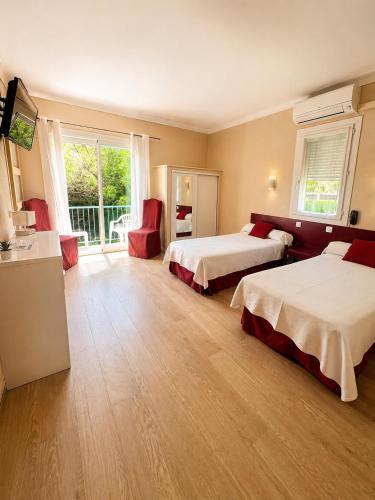 a hotel room with two beds and a balcony at Hôtel Saint Jacques in Sorède
