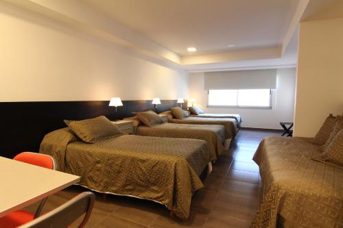 a hotel room with four beds and a table at 646 Hotel Balcarce in Balcarce