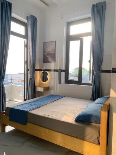 a bedroom with a bed and two windows at CoCo SEA in Mui Ne