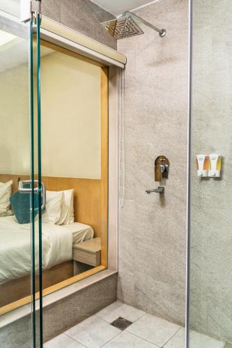 a bathroom with a glass shower with a bed at Marlo Hotels in Kathmandu