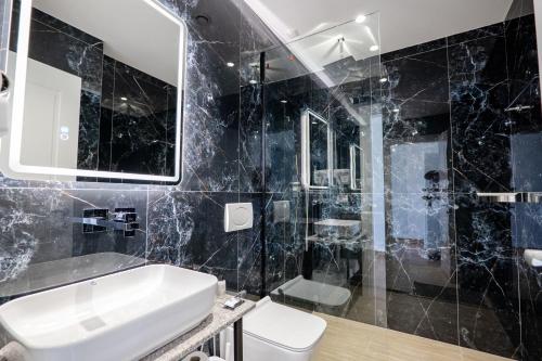 a black bathroom with a sink and a mirror at Vila 2M in Sarandë