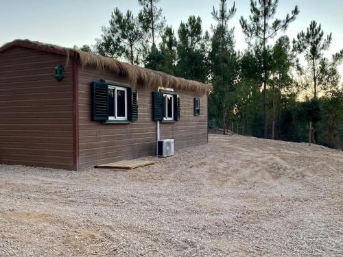 a small cabin with two windows on a gravel yard at Casa Silvestre in Melides