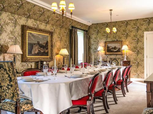 a dining room with a long table and red chairs at Villa Abbotsford by Interhome in Darnick