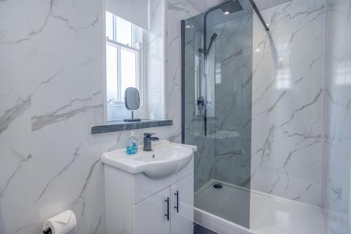 a white bathroom with a sink and a shower at Ty Mor in Tenby