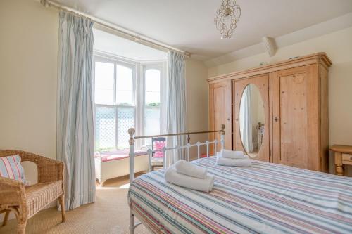 a bedroom with a bed and a chair and a mirror at Ty Mor in Tenby